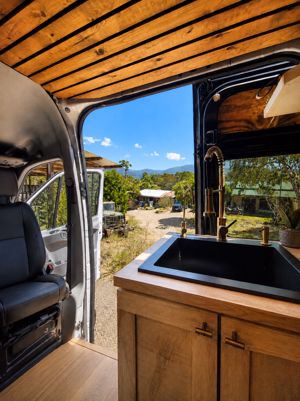Cuisine compacte en bois avec grand évier noir et accès direct à l’extérieur.