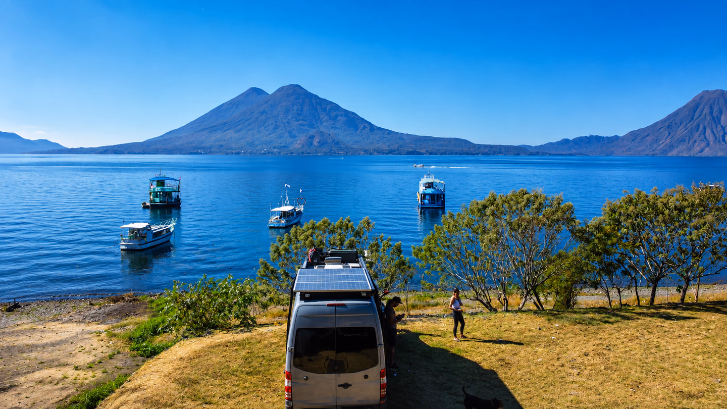 Fourgon aménagé au bord d’un lac volcanique après de longues heures de route.